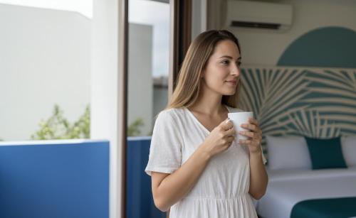 a woman is holding a cup of coffee at Kue Hotel Maafushi in Maafushi