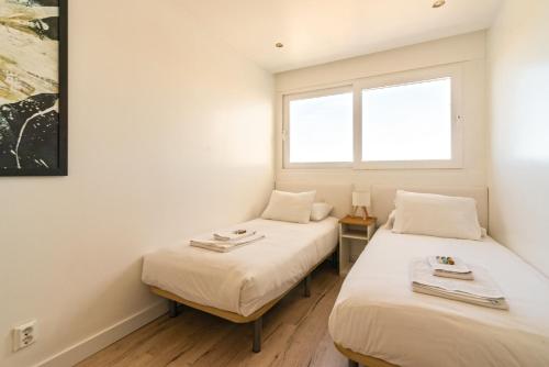 two beds in a room with two windows at Modern 2 Bedroom Apartment with Balcony in Cascais in Cascais