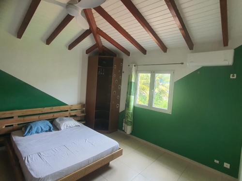 Un dormitorio con una cama y una pared verde. en Villa Doubs Etage 1, en Les Abymes