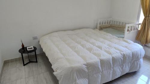a white bed in a white bedroom with a table at Casa Tafí in Tafí Viejo