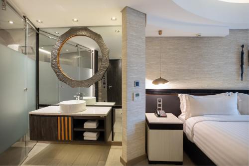 a bathroom with a bed and a sink and a mirror at Tribe Hotel, Nairobi, a Member of Design Hotels in Nairobi