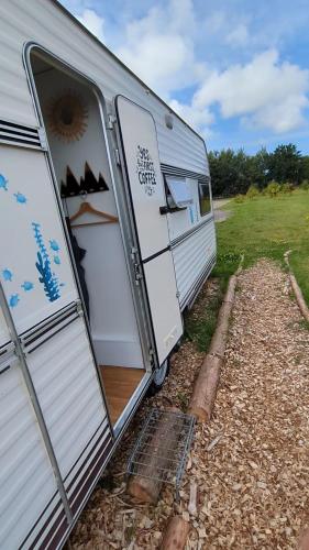 an rv with its doors open in a field at Gerestylde vintage caravan "Zee" met luxe badkamer bij "de Kapitein" in 't Horntje