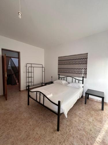 a bedroom with a large bed and a table at Tarrafal Ecodécor Rooms in Tarrafal