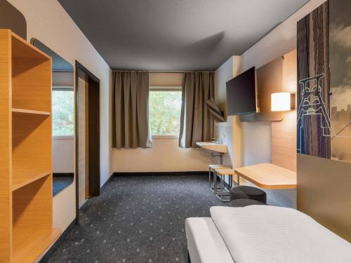 a room with a bed and a desk and a table at B&B HOTEL Würzburg-Ost in Würzburg