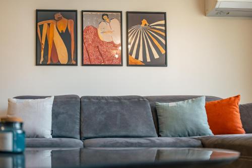 a couch in a living room with four pictures on the wall at TRINAVIS Boutique Apartments, OWN PRIVATE PARKING, City Center, Entire Apartment in Veliko Tŭrnovo