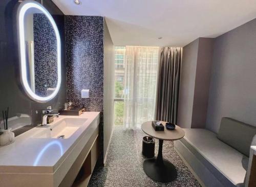 ein Badezimmer mit einer Badewanne, einem Waschbecken und einem Tisch in der Unterkunft Yue Tower TOP PLAY eSports Hotel Beijing Road Branch in Guangzhou