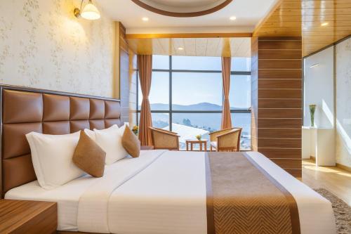 a bedroom with a large bed with a large window at Yashshree Jai Hotel & Banquet in Darjeeling