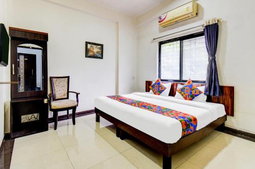 a bedroom with a bed and a chair in it at FabExpress Sahil Residency in Pune