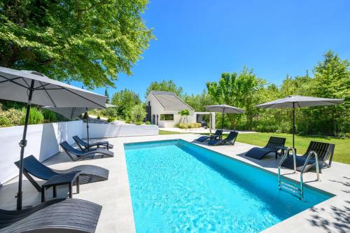 a swimming pool with lounge chairs and umbrellas at La Casa Del Rio in Kymi