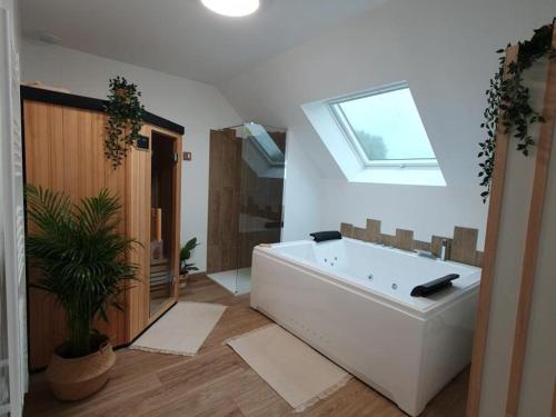 a bathroom with a large white tub and a skylight at Gîte à Luzillé avec jardin privé et climatisation - FR-1-381-532 in Luzillé