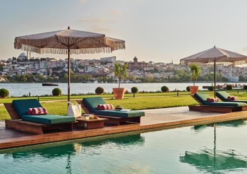 una piscina con sillas y sombrillas junto al agua en Aliée Istanbul - A Paris Society Collection Hotel, en Estambul