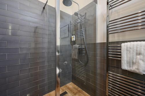 a bathroom with black tiled walls and a shower at The Cow Shed in Groombridge