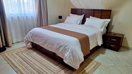 a bedroom with a large bed with a wooden headboard at Oreville Apartments in Goma
