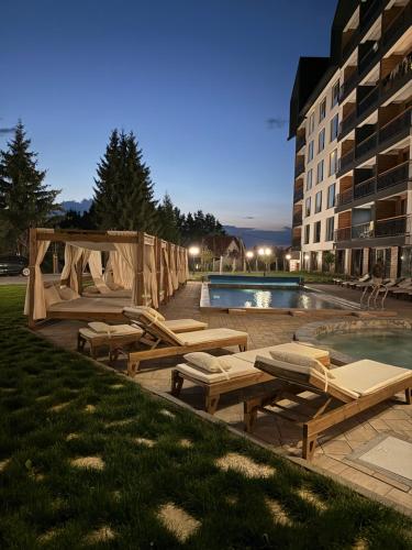 a swimming pool with lounge chairs and a building at UN lux - Residence Hill in Kopaonik