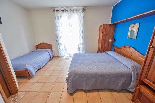 two beds in a bedroom with blue walls at Agriturismo La Panoramica in Assisi