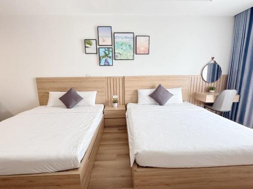 two beds in a hotel room with white sheets at TMS Quy Nhơn - Hupa Apartment View Biển in Quy Nhon