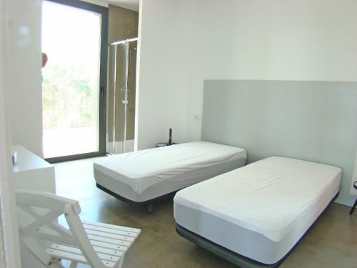 two beds in a white room with a window at Villa en el campo cerca de la playa in Armentera