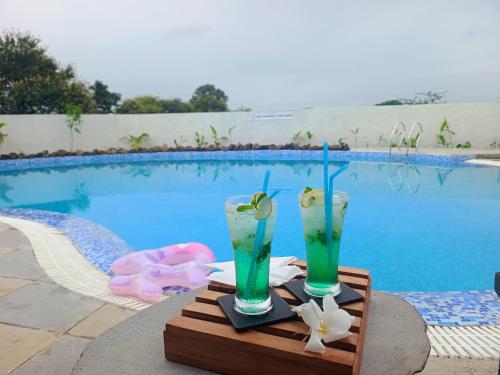 two drinks on a tray next to a swimming pool at Sterling Tipeshwar in Pahāpal