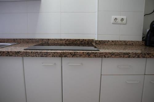 a kitchen with white cabinets and a counter top at Sky New in Málaga