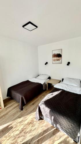 two beds in a room with white walls and wooden floors at Domki Pasieka Domek D in Przeczyce