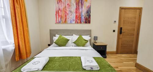 a bed with green and white sheets and pillows at St Martins Guest House - Rooms Only in Tranent