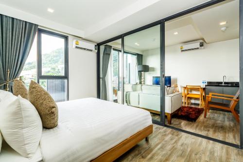 a bedroom with a bed and a living room at Deck Condo private apartment by Lofty in Patong Beach