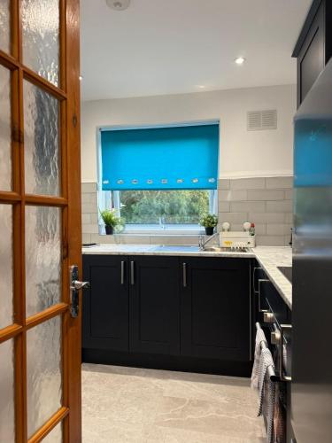 a kitchen with black cabinets and a window at Modern City Flat, Walk to Hatfield House, Trains and University in Hatfield