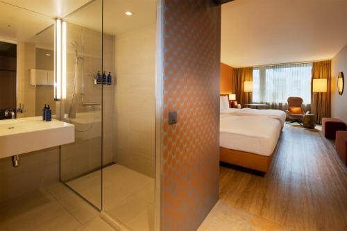 a hotel room with a bed and a shower and a bathroom at Radisson Blu Hotel, Lucerne in Luzern