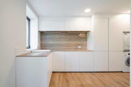 eine Küche mit weißen Schränken und einem Holzboden in der Unterkunft Relax in Santiago de Compostela in Vedra