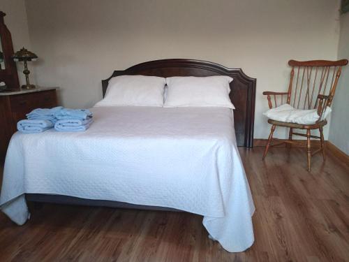 a bedroom with a bed with white sheets and a chair at El Olivo in Gualeguaychú