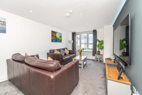 a living room with a leather couch and a flat screen tv at Super Prime Luxury Waterfront View DBay by TBA in Saint Davids