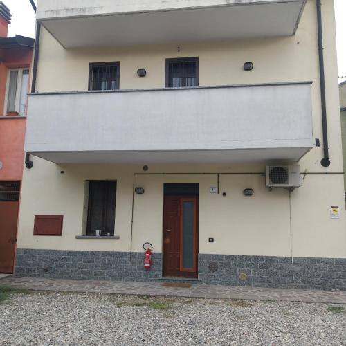 a white building with a red door and a fire hydrant at B&B linate in Peschiera Borromeo