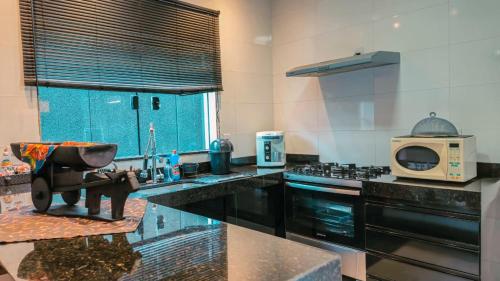 a large kitchen with a sink and a microwave at Casa Belmond in Capitólio