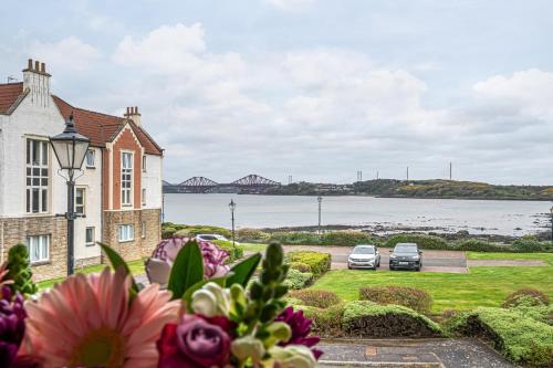 two cars parked in front of a house with flowers at Super Prime Luxury Waterfront View DBay by TBA in Saint Davids