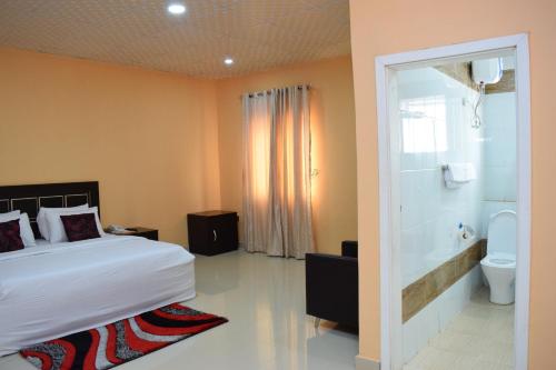 a bedroom with a bed and a bathroom with a toilet at Charriot Hotels in Abuja
