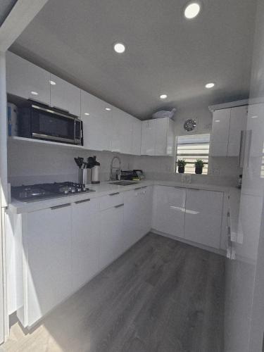 a kitchen with white cabinets and a sink and a microwave at Gallego Deluxe Rental in Key Largo