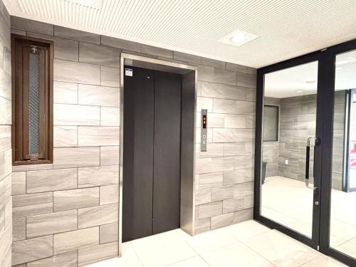 a door in a lobby with a stone wall at 福の荘 美野島 in Fukuoka