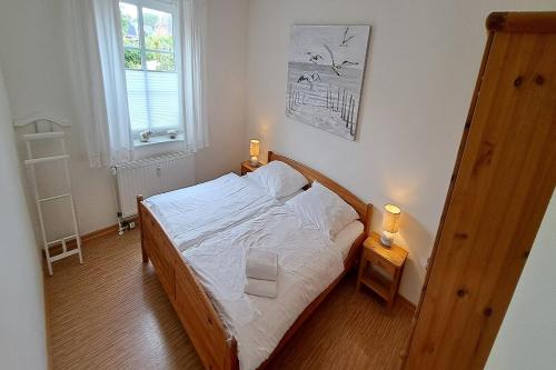 a bedroom with a bed with white sheets and two lamps at Ferienwohnung Strandläufer Dagebüll in Dagebüll