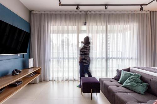 a person standing in a living room looking out the window at Charlie Itaim in Sao Paulo
