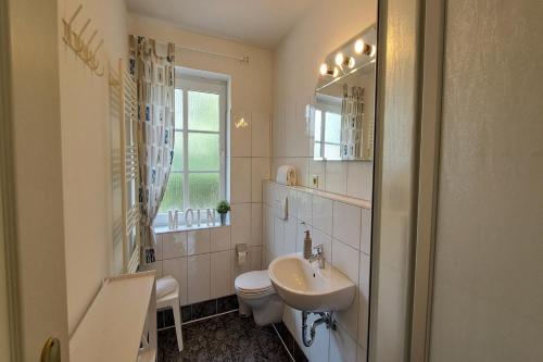 a white bathroom with a sink and a toilet at Ferienwohnung Strandläufer Dagebüll in Dagebüll