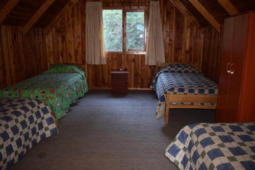 a bedroom with three beds in a wooden cabin at Vista Hermosa Conguillio in Conguillío