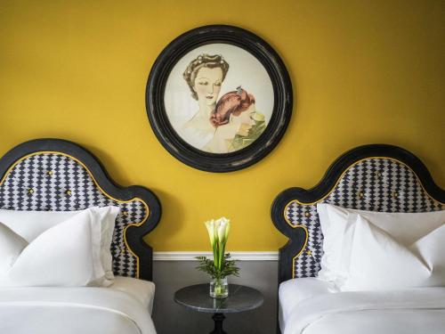 a room with two beds and a picture on the wall at Hotel de la Coupole - MGallery in Sa Pa