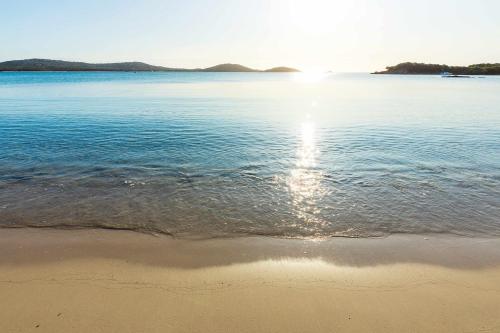 a beach with the sun reflecting in the water at Hôtel Spa & Restaurant - Son de Mar in Porto-Vecchio