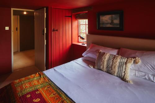 een slaapkamer met een wit bed met rode muren bij Heale Farm Cottage in Trentishoe