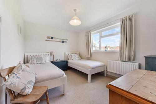 a bedroom with two beds and a window at 21 Owers Way, West Wittering in West Wittering