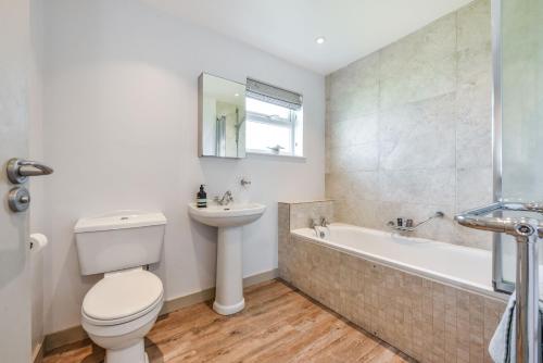 a bathroom with a toilet and a tub and a sink at 21 Owers Way, West Wittering in West Wittering