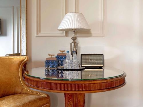 a table with a lamp on it next to a chair at Bachleda Luxury Hotel Kraków - MGallery Collection in Kraków
