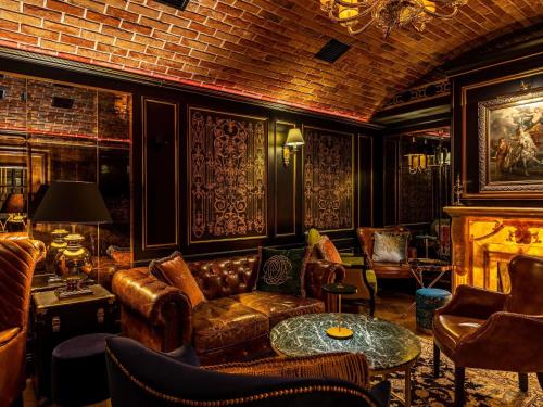 a living room with leather furniture and a fireplace at Bachleda Luxury Hotel Kraków - MGallery Collection in Kraków