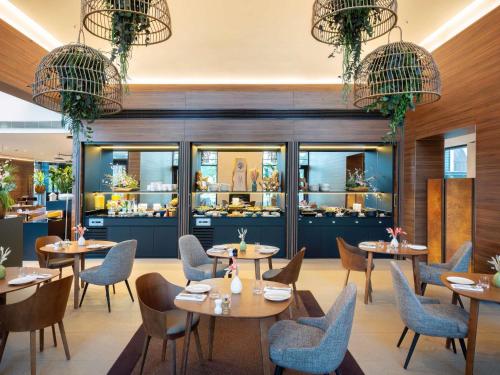 Un restaurante con mesas y sillas en una sala. en Le Domaine des Vanneaux Golf & Spa L'Isle Adam - MGallery Collection, en LʼIsle-Adam