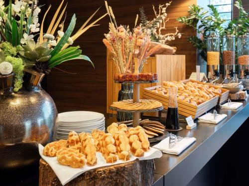 Un buffet con aperitivos y otros alimentos en una mesa. en Le Domaine des Vanneaux Golf & Spa L'Isle Adam - MGallery Collection, en LʼIsle-Adam